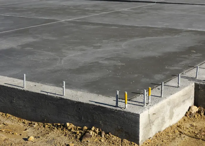 Thick concrete foundation surrounded by dirt on two corners