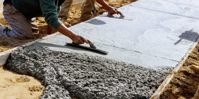 Two concrete workers troweling a concrete sidewalk.