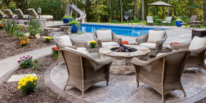 Decorative concrete patio beside an inground pool with patio furniture on it
