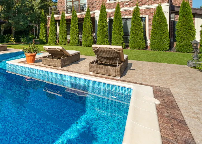 Decorative concrete pool deck in front of a beautiful brick stone house